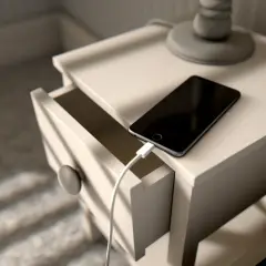 Czarny telefon podłączony do ładowarki na stoliku nocnym. Zastanawiasz się, jak szybko rozładować telefon? Ten obraz pokazuje, jak tego nie robić.