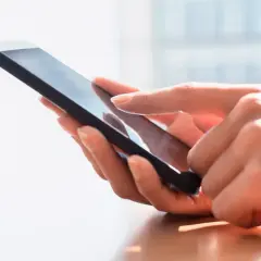 Dłoń dotyka ekranu smartfona, szukając archiwum SMS.