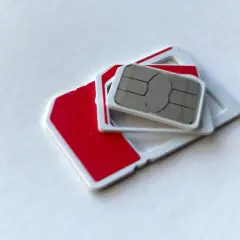 Dwie karty SIM, jedna czerwona, druga z metalowym chipem, leżą na białym tle. Szukasz najtańszej karty SIM?