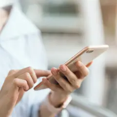 Dłoń trzymająca telefon, szukająca instrukcji, jak wyłączyć tryb awaryjny w telefonie.