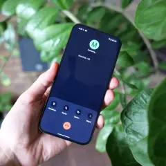 Dłoń trzyma smartfon z ekranem połączenia wychodzącego. Widnieją tam dziwne numery i ikony.