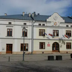 Rektorat w mieście, gdzie kierunkowy 13 wskazuje drogę. Budynek z zegarem i polskimi flagami.