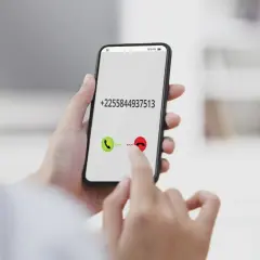 Dłoń trzyma smartfon z numerem +2255844937513. Palec wskazuje przycisk odbierania połączenia, jakby wybierał kierunkowy 40.