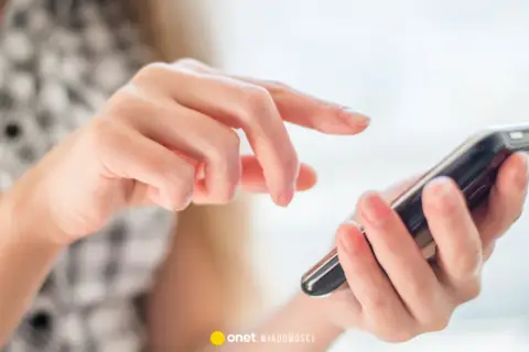 Dłoń z telefonem, palce przesuwają po ekranie. Czy to kierunkowy 33 jakie miasto?