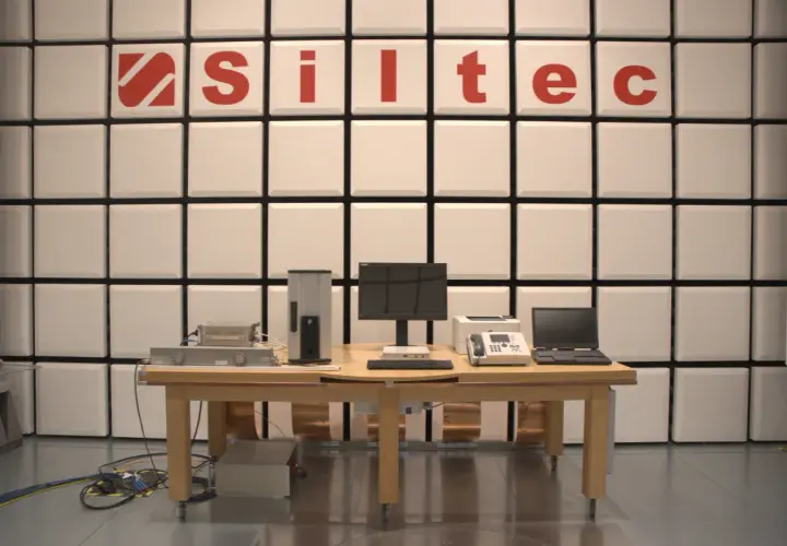 Laboratorium testowe z urządzeniami elektronicznymi i logo "Siltec". W tle ściana z paneli akustycznych, chroniąca przed zakłóceniami, jak podczas burzy (tempest).