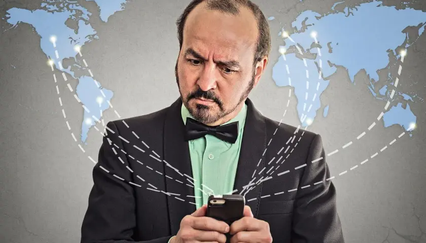 Mężczyzna zmartwiony patrzy na telefon, zastanawiając się, co to roaming i jak działa globalna sieć.