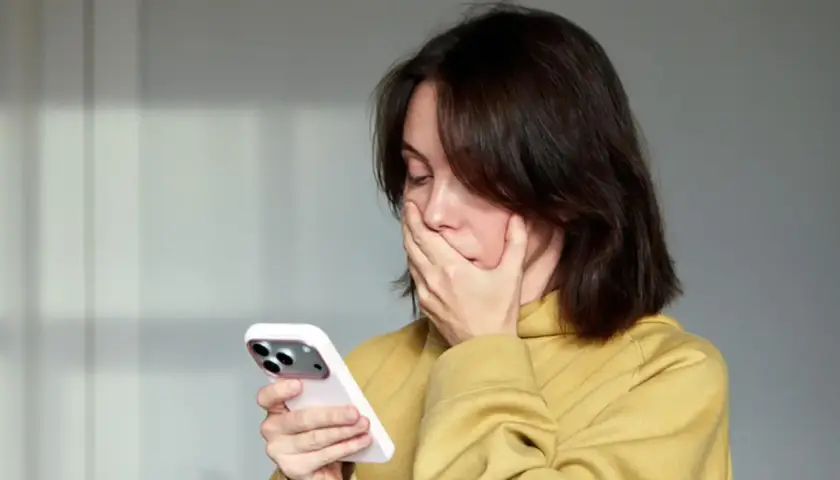 Zaskoczona kobieta zasłania usta dłonią, patrząc na telefon. Czyżby zobaczyła coś niepokojącego, a może to numer 883 co to za numer?