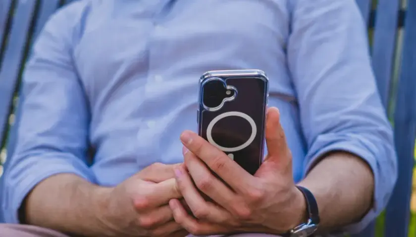Mężczyzna w niebieskiej koszuli trzyma telefon z okrągłym wzorem. Czuć w tym nowoczesną haptykę.