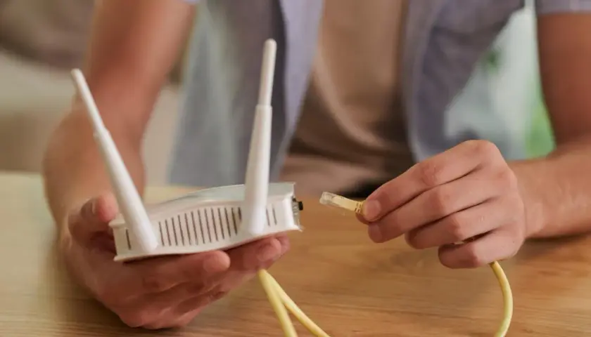 Ręce podłączają kabel do routera, próbując rozwiązać problem **netia brak internetu**.