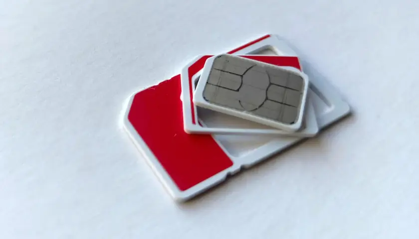 Dwie karty SIM, jedna czerwona, druga z metalowym chipem, leżą na białym tle. Szukasz najtańszej karty SIM?