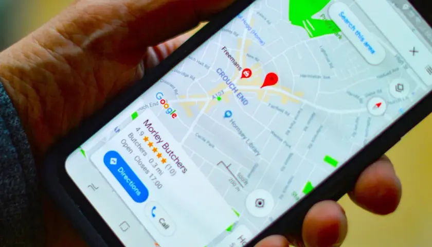 Dłoń trzyma smartfon z mapą Google. Widoczna jest pinezka Google wskazująca lokalizację "Morley Butchers".