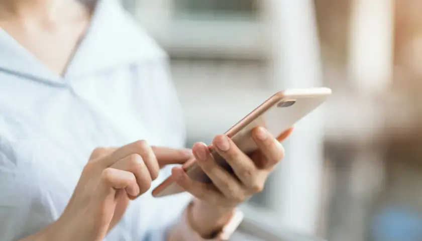 Dłoń trzymająca telefon, szukająca instrukcji, jak wyłączyć tryb awaryjny w telefonie.