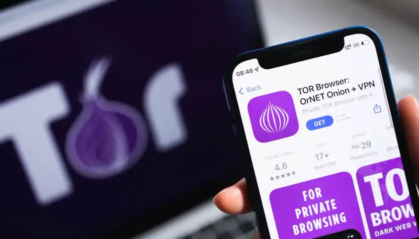 Smartfon z aplikacją TOR Browser, obok laptop z logo sieci Tor. Prywatność w sieci.