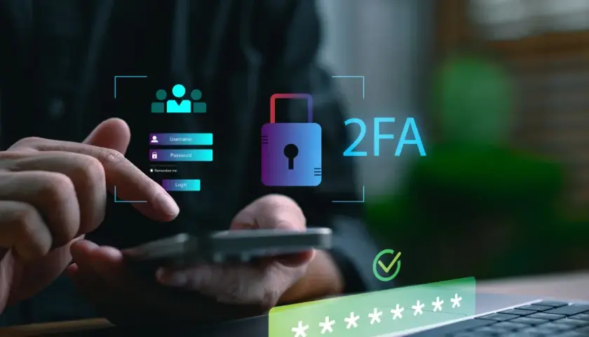 Dłoń wpisuje dane logowania na smartfonie, obok widnieje ikona kłódki i napis 2FA co to, symbolizujące podwójne uwierzytelnianie.