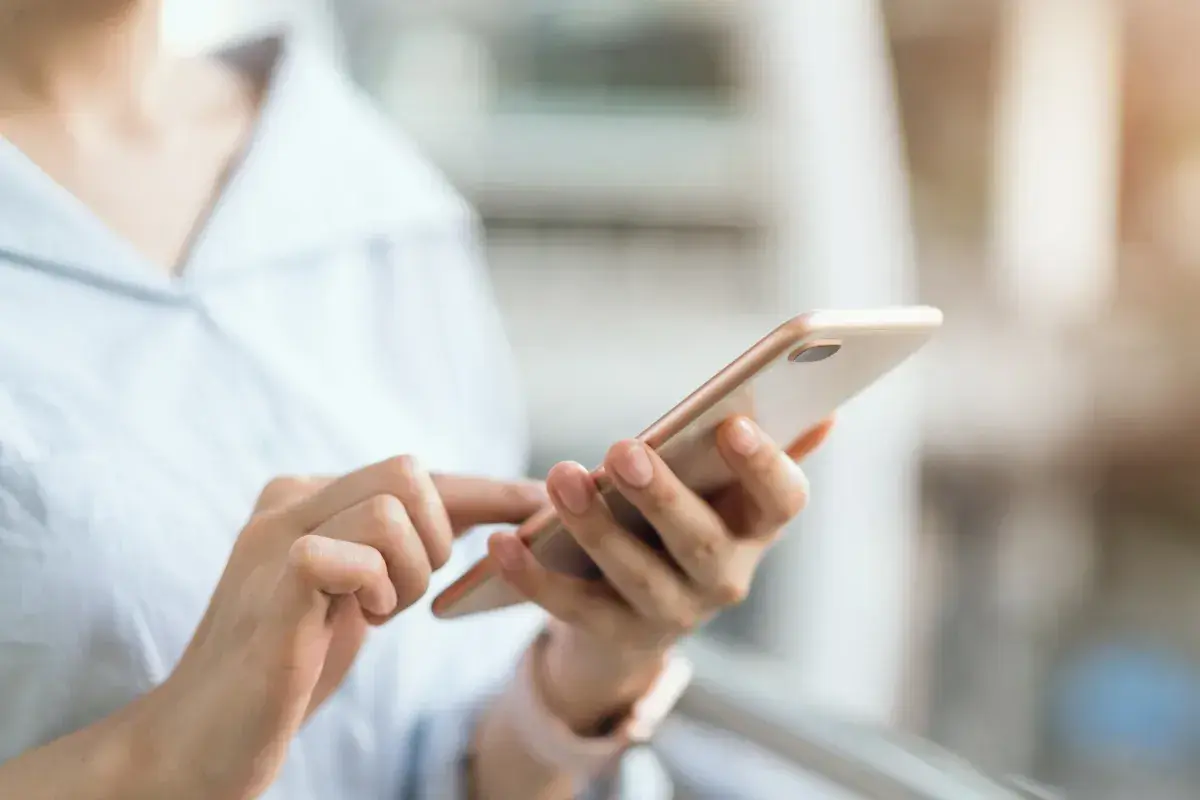 Dłoń trzymająca telefon, szukająca instrukcji, jak wyłączyć tryb awaryjny w telefonie.
